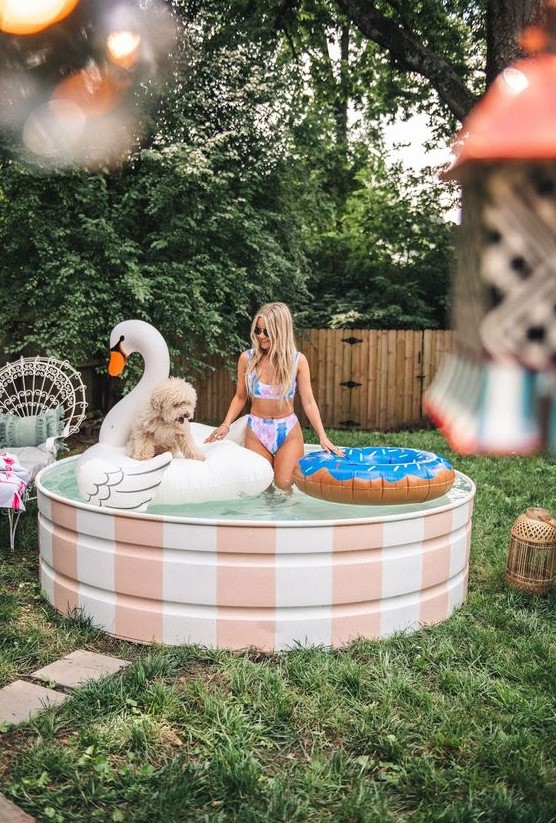 A small and cute stock tank pool with white and pink stripes and cool floats is a lovely space for your backyard.