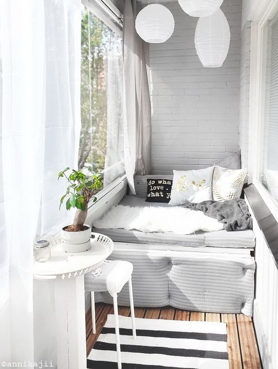 A small balcony with a daybed, a tiny table and stool, paper lanterns and sheer curtains is very welcoming.
