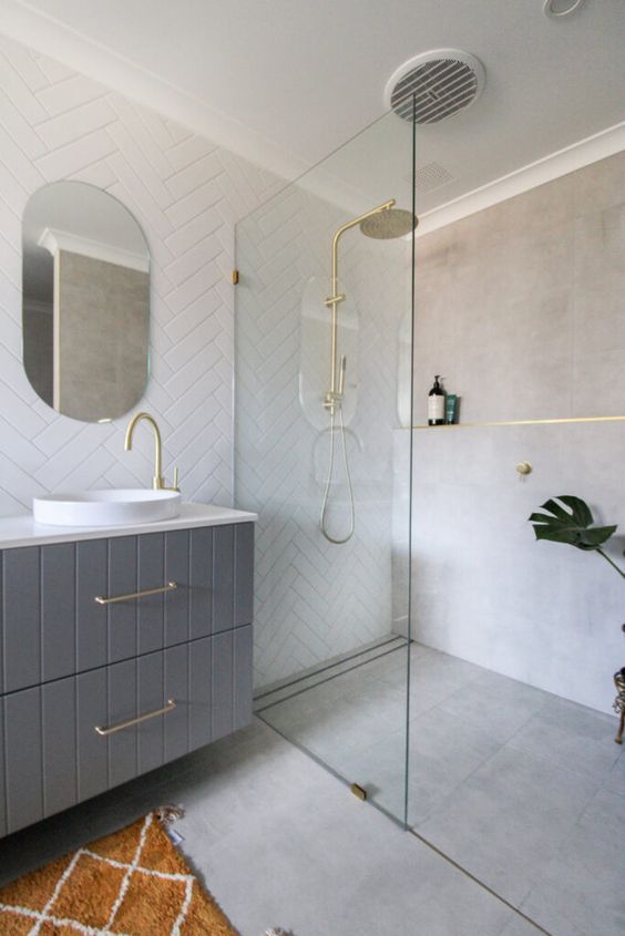 A small contemporary bathroom with grey concrete tiles and white herringbone ones, a grey vanity, gold fixtures is cool.