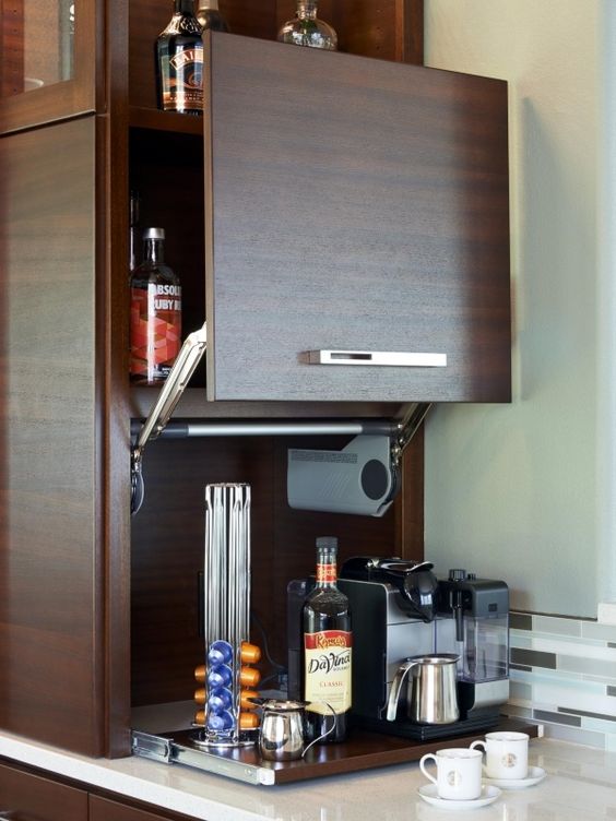 A small dark stained cabinet with a sliding door and a mini coffee station inside, on a retractable shelf is a stylish idea.