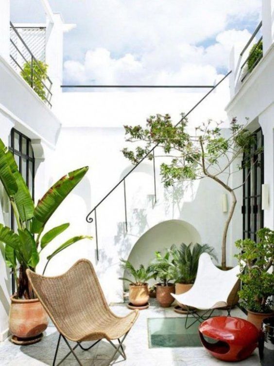 A small terrace with a couple of chairs, potted plants, and a bold red candle lantern is chic and stylish.