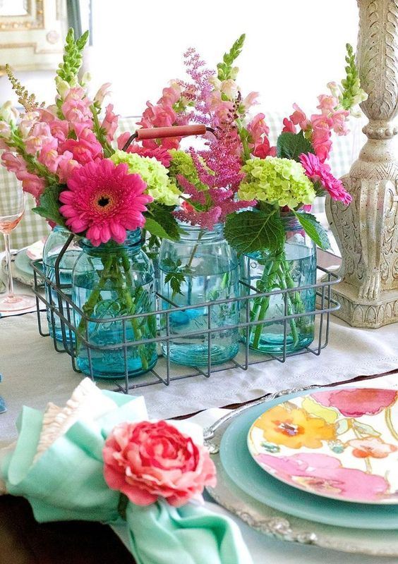 A wire basket with blue jars and pink and green blooms for a slight rustic touch and a strong summer feel.