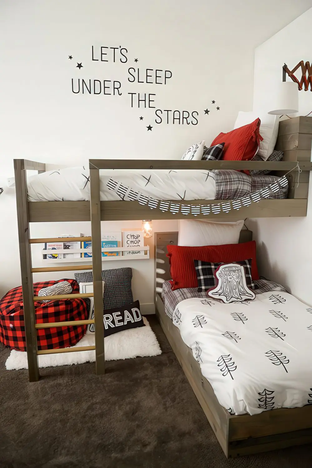 A cozy bunk room with a nature-inspired theme, featuring wooden bunk beds and a "Let's Sleep Under the Stars" wall decal. Red and black plaid pillows and a reading nook create a warm and inviting atmosphere.
