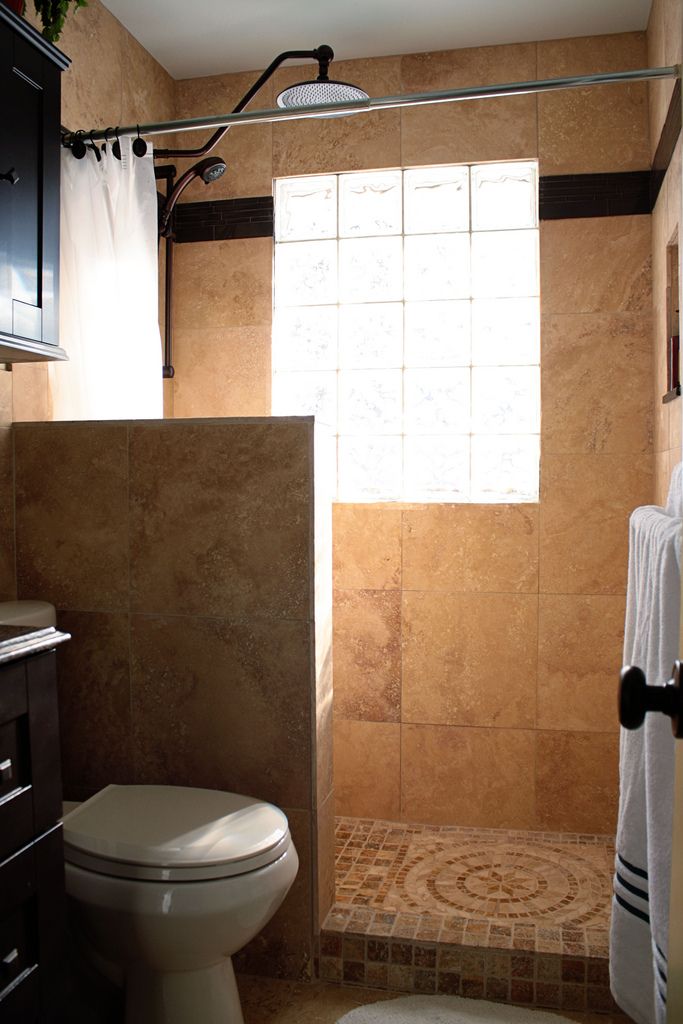 A warm-colored bathroom with a pony wall and sandy tiles, it's small ye functional and feels airy thanks to the pony wall.