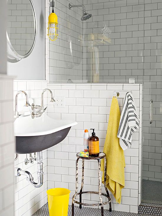 A mid-century modern bathroom clad with white subway tiles, with a half wall, a vintage sink and touches of yellow for a brighter look.