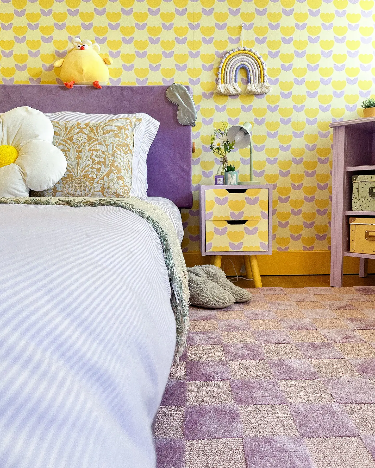 This space is pure joy! The yellow and purple tulip wallpaper sets a cheerful vibe, perfectly matched with a soft purple headboard and a mix of floral and fluffy pillows. The custom nightstand ties it all together—playful, cozy, and bursting with personality. (@hilaryscolourfulhome).