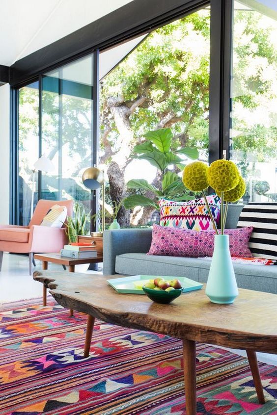 Bright yellow blooms, printed colorful pillows, a bright boho rug make the living room feel like summer.