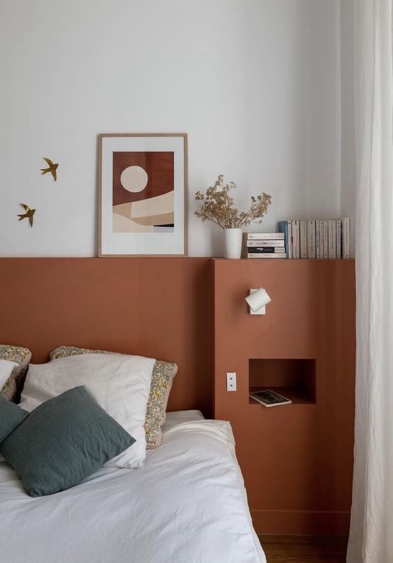 This terracotta headboard goes from wall to wall and adds storage space to the bedroom, with some decor on top the shelf.