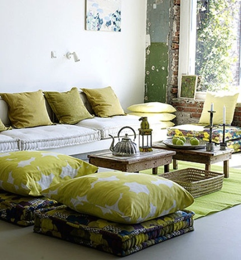 A summer living room in mustard shades, with lots of pillows and cushions and some fruits as additional decor.