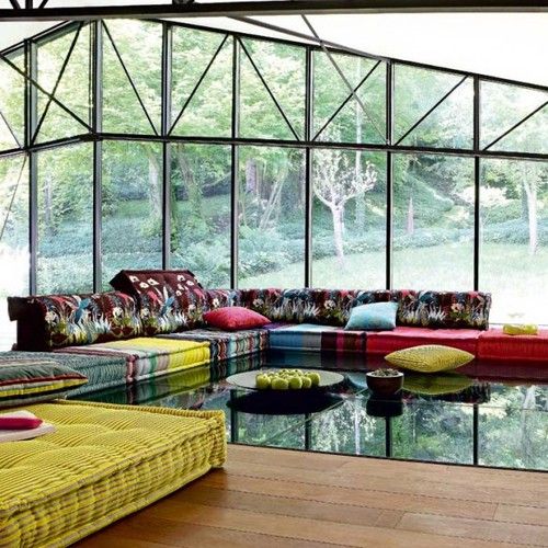 A bright summer living room with colorful cushions and pillows, bold floral and botanical prints and glazed walls to feel like outdoors.