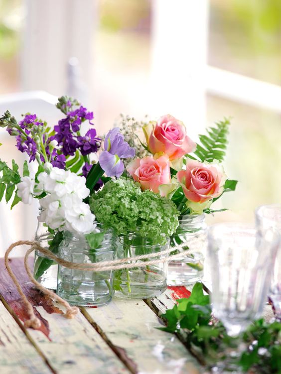 Clear jars with various summer blooms and twine are a cool and simple summer decoration or centerpiece.
