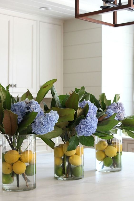 Clear vases with citrus and blue hydrangeas and magnolia leaves for chic traditional southern decor.