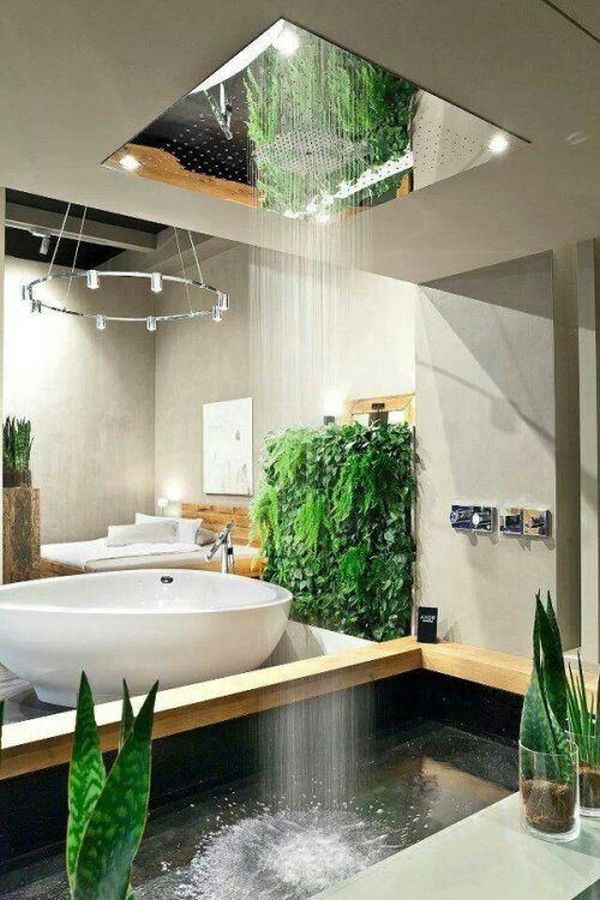 A contemporary neutral bathroom with an oval-shaped bathtub and greenery and a rain shower from above that feels like real rain.