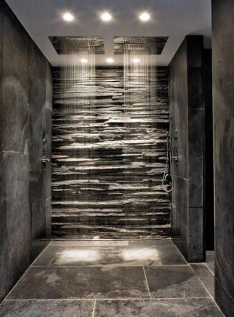 A beautiful shower space clad with stone tiles and with a faux stone wall plus two rain shower heads is a great idea to rock.