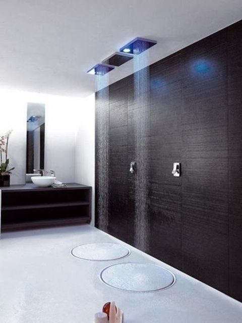 A minimalist shower with a dakr accent wall, just two rounds on the floor and colored lights plus two rain showers for a minimalist bathroom.