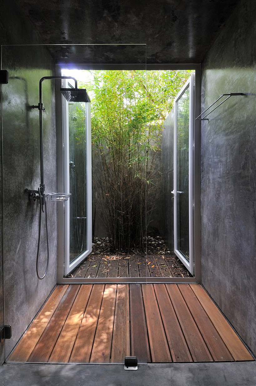 A contemporary outdoor-indoor shower with a wooden floor, stone walls and an exit to the private backyard.