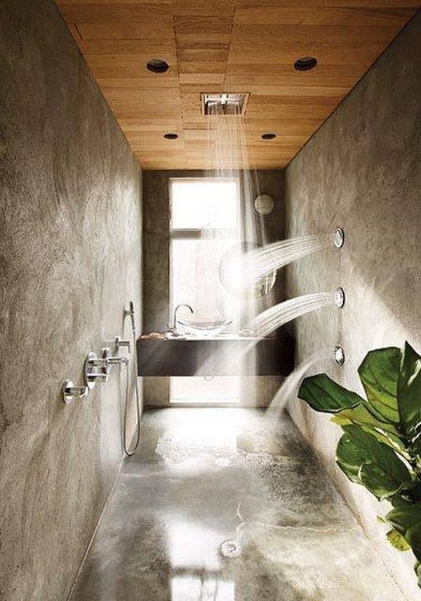 A modern tropical bathroom with a built-in vanity and sink, concrete walls and a floor, a rain shower and shower integrated into the walls.