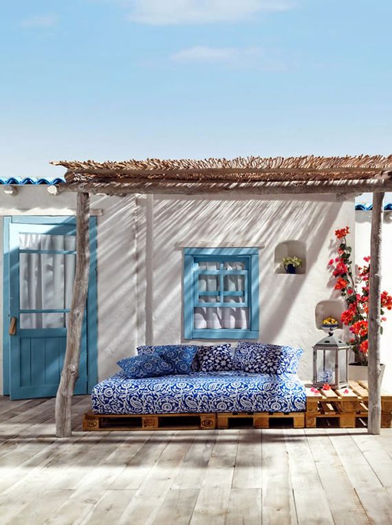 A cheerful Greek summer terrace with pallet furniture, bright blooms and candle lanterns plus bold textiles.