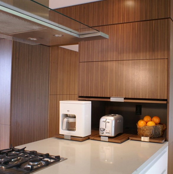 A sleek cabinet with retracting shelves and appliances and fruits in a bowl for a minimalist kitchen.