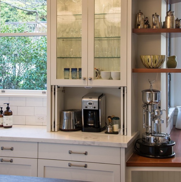 A glass cabinet with a lower part with a folding door and a coffee machine and toaster hidden here to keep the kitchen decluttered.
