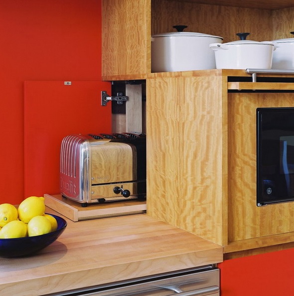 A chic toaster on a retracting board hidden in the back part of a cabinet with built-in appliances.