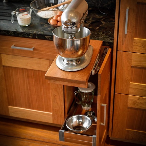 A narrow cabinet with retractable shelves and a mixer plus additional stuff under it.