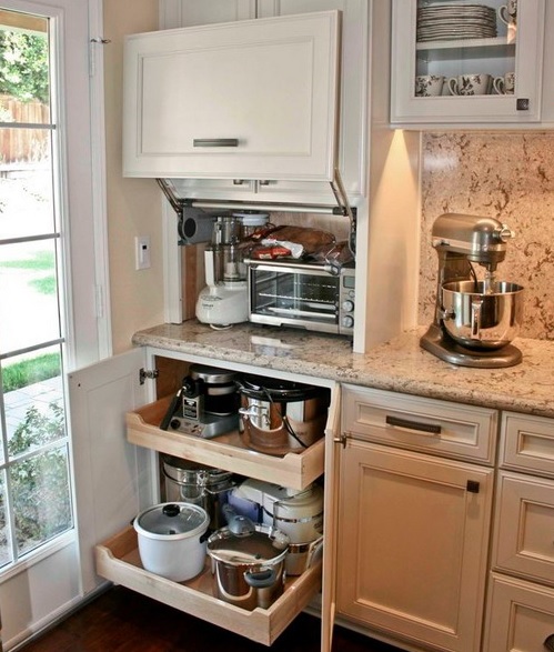 A small cabinet with several appliances and a lower cabinet with retractable shelves with pots and appliances for a functional kitchen.