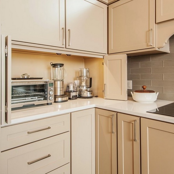A small neutral cabinet with folding doors hides several kitchen appliances and gives the kitchen a neater look.