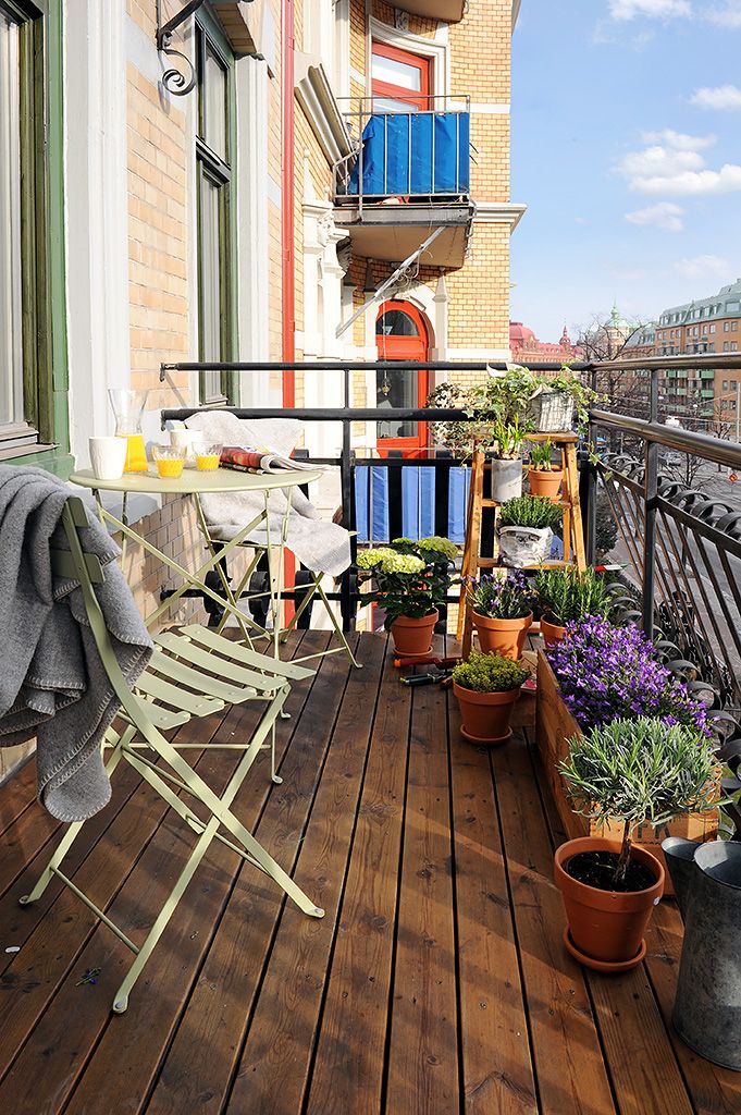 A small balcony with folding metal furniture and potted geenery and blooms is a simple and cozy space to enjoy fresh air.