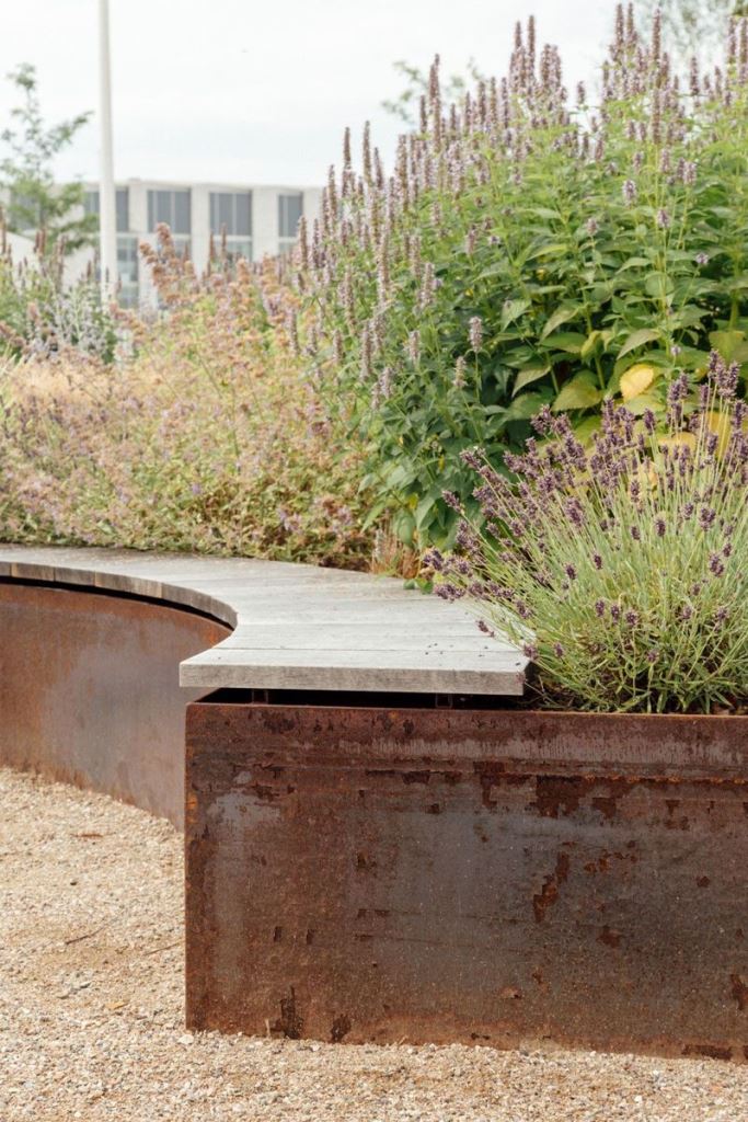 This curved raised garden bed with lots of flowers is paired with a curved bench.