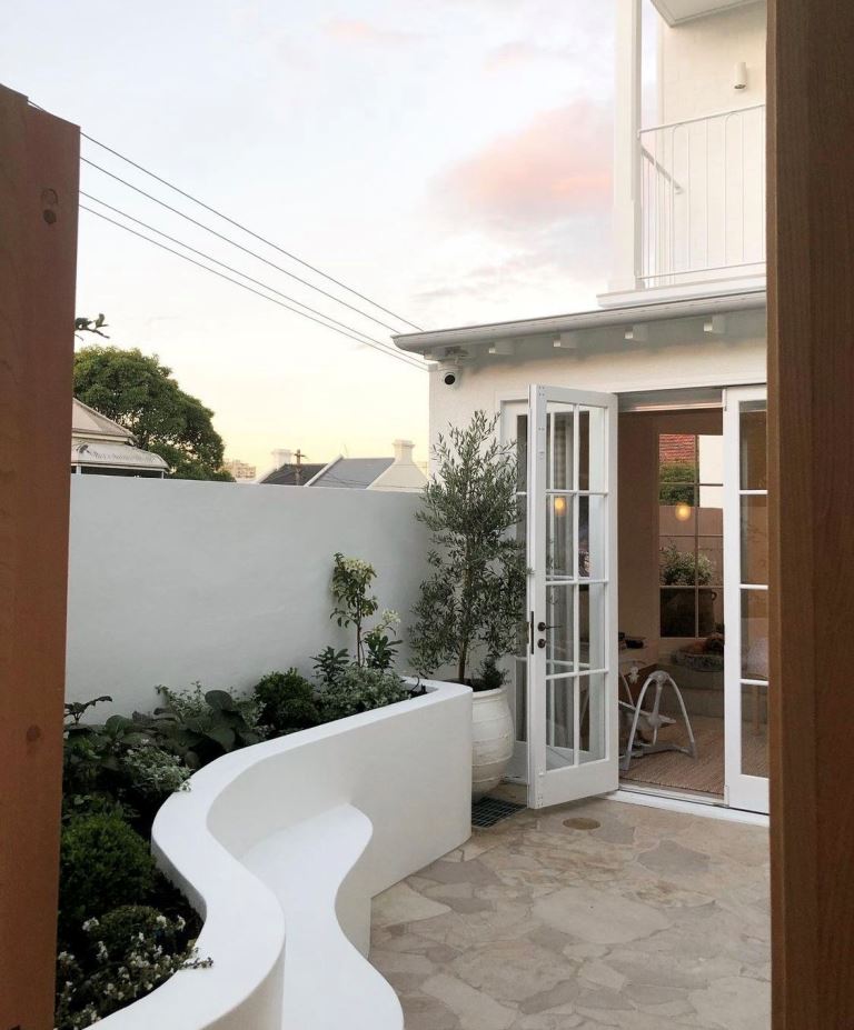 The small yard is styled with a white raised garden bed and bench that set the tone and make the nook refined.