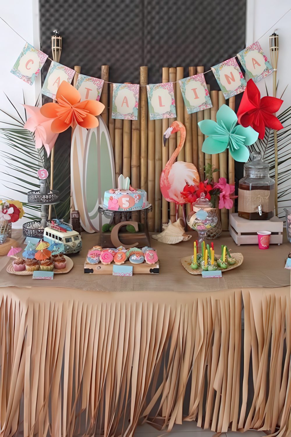 A colorful girl's baby shower dessert table with touches of red, turquoise and peahcy pink, a flamingo, a retro bus and a bright banner.