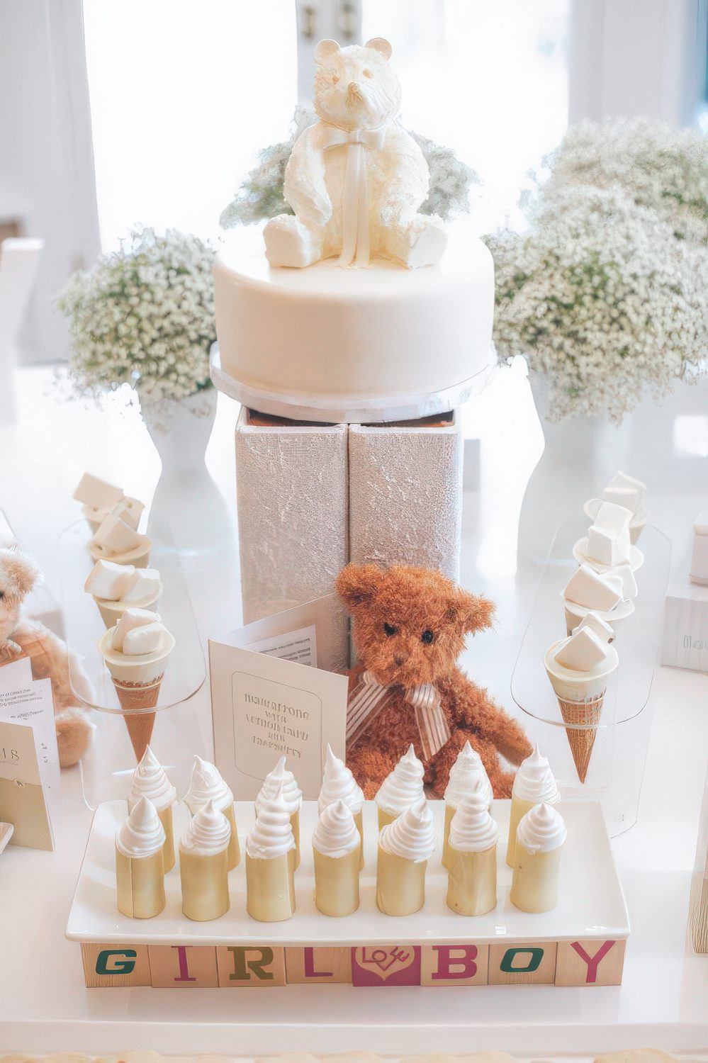 A neutral dessert table with baby's breath, a teddy bear, a teddy bear cake looks totally gender neutral.