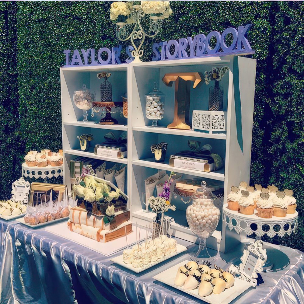 An off-white and grey dessert table with a box-shaped shelf and lots of sweets on stands and even on books.