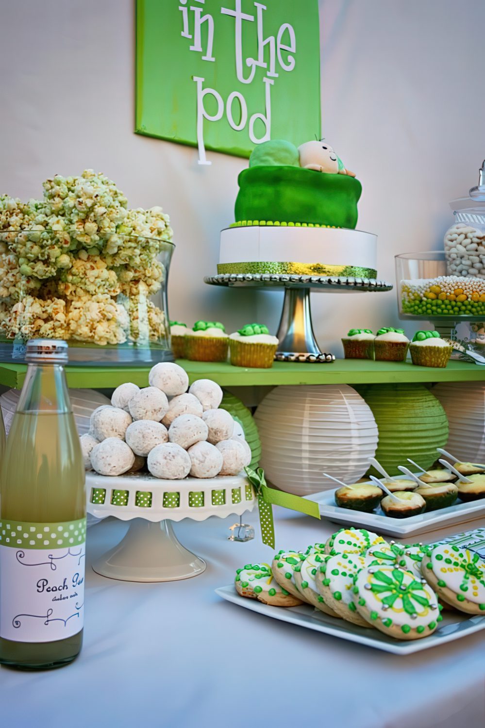 A green and white dessert table with various stands, trays and a sign over it.