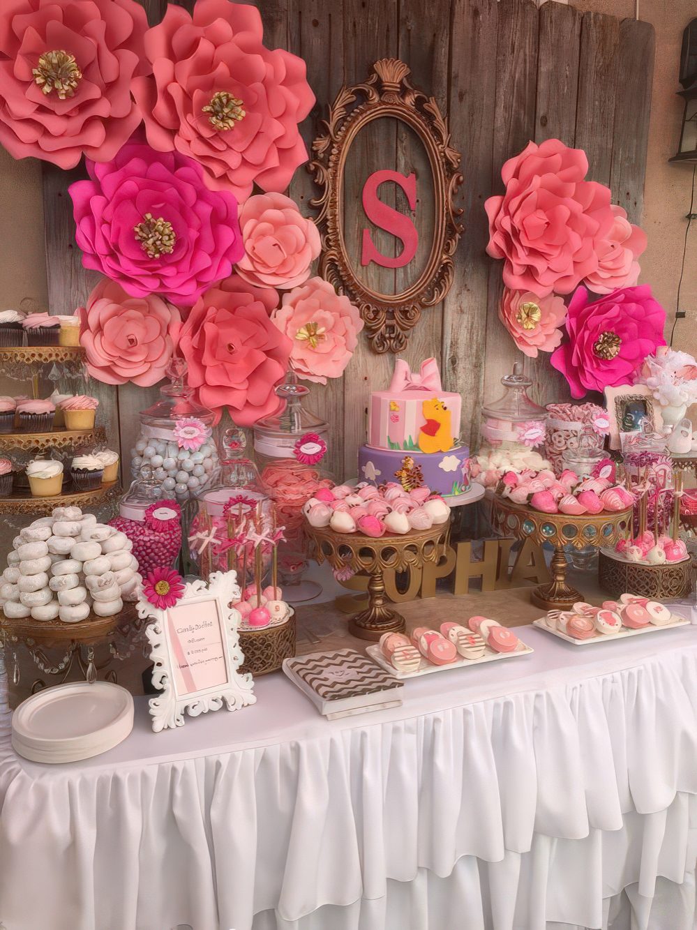 A bright pink and fuchsia dessert table with large paper flowers, touches of brass, monograms and letters.