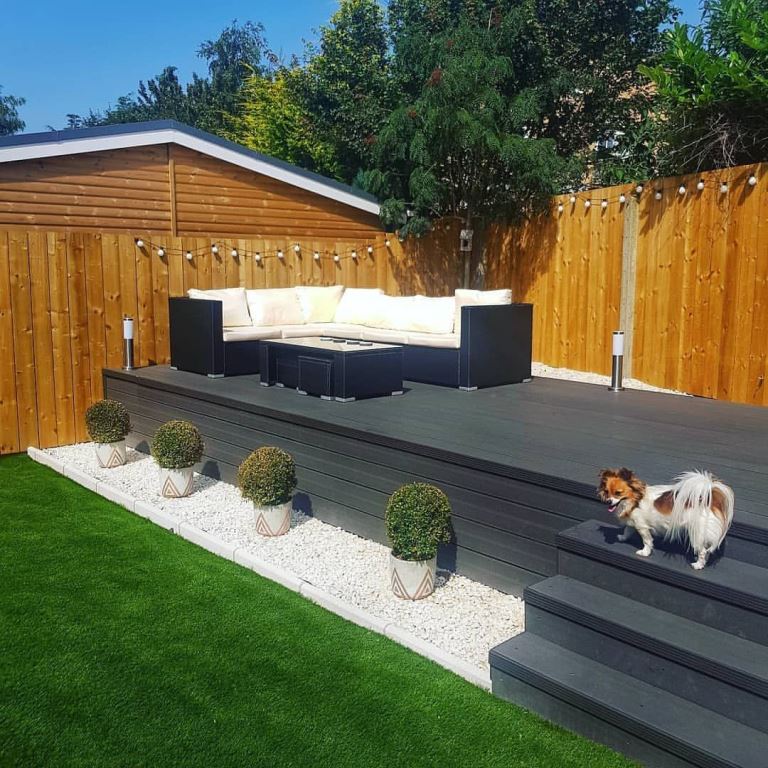 The dark raised deck is styled with black furniture and potted plants. 

(via instagram).