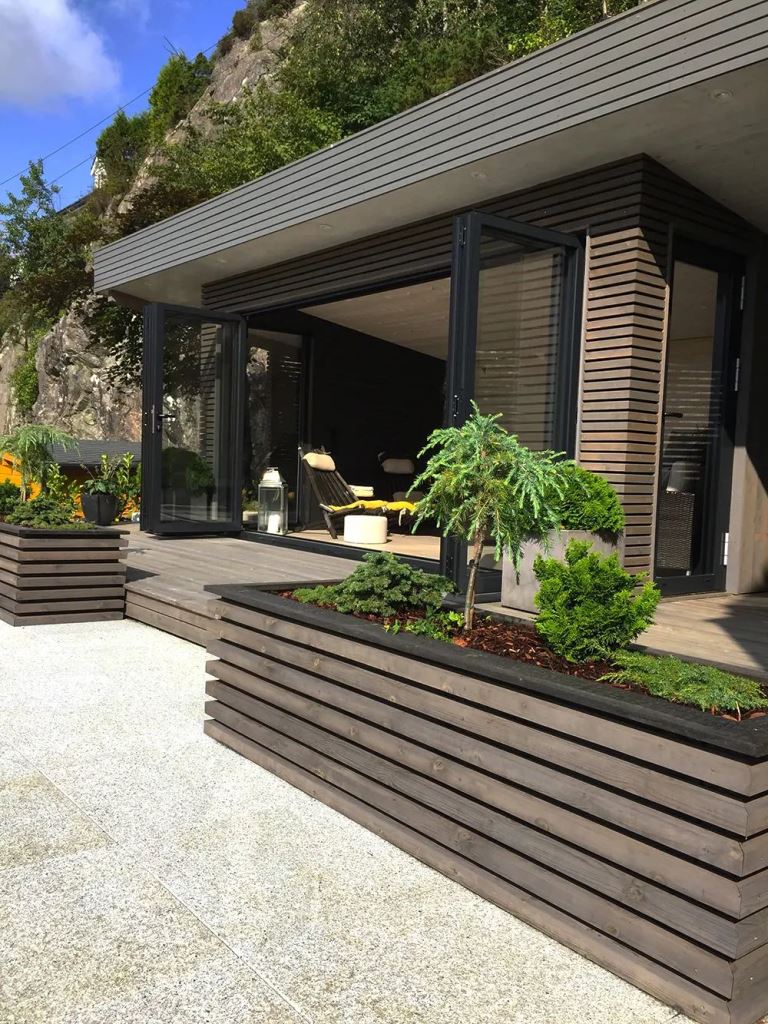 The contemporary outdoor space shows off a stained deck and garden beds that match the slatted facade perfectly.