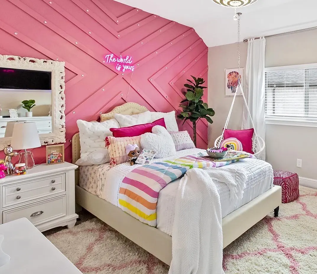 If you love color, this room is a dream! The bold pink geometric wall, twinkling lights, and layers of cozy bedding make it feel stylish yet inviting. A hanging chair and rainbow accents add a fun, playful energy—perfect for a teen who loves a little glam.

(@decor_for_kids).