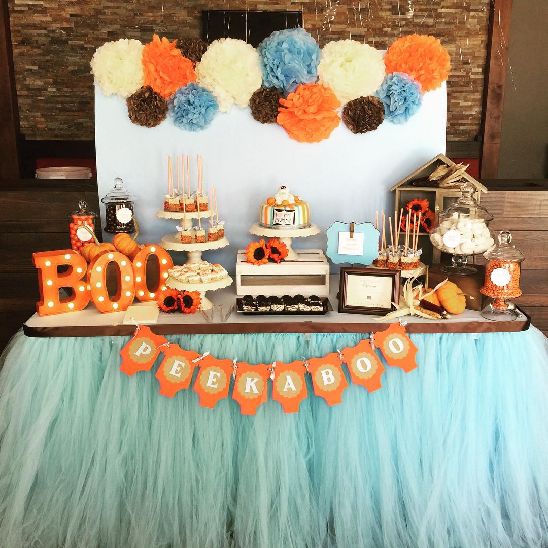 A playful mix of spooky and sweet, this Halloween-themed baby shower dessert table features candy jars, pumpkin decor, and a “Peekaboo” banner, all wrapped in festive orange and soft blue tulle.

(@bizziebeecreations).