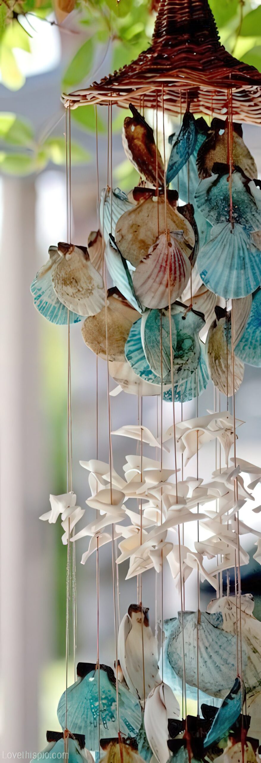 A catchy chandelier with blue and white seashells, starfish and a wicker base is a cool idea for a beach or boho space or for outdoors.