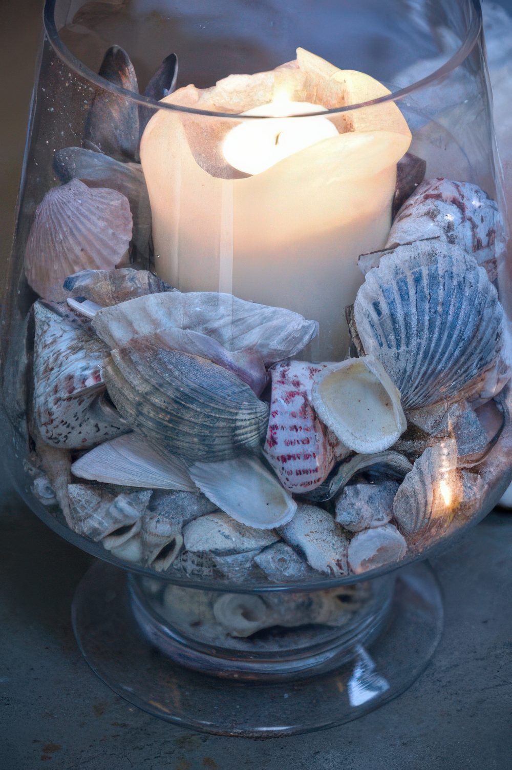 A cool decoration of a glarge glass, seashells and a candle in the center is a cool and easy DIY.