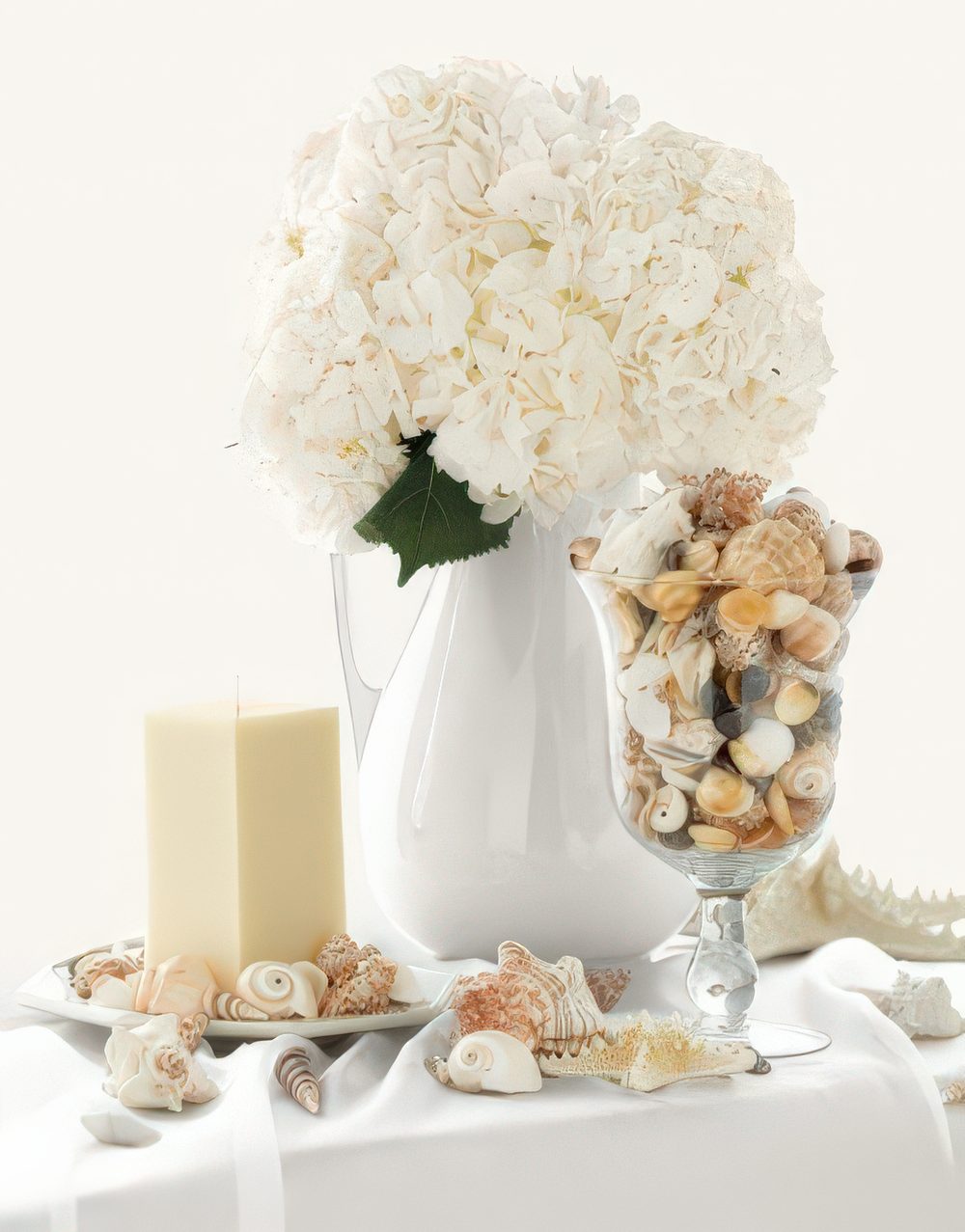 Seashells in a tall glass and all around on the table plus white hydrangeas look very chic and feel nautical.