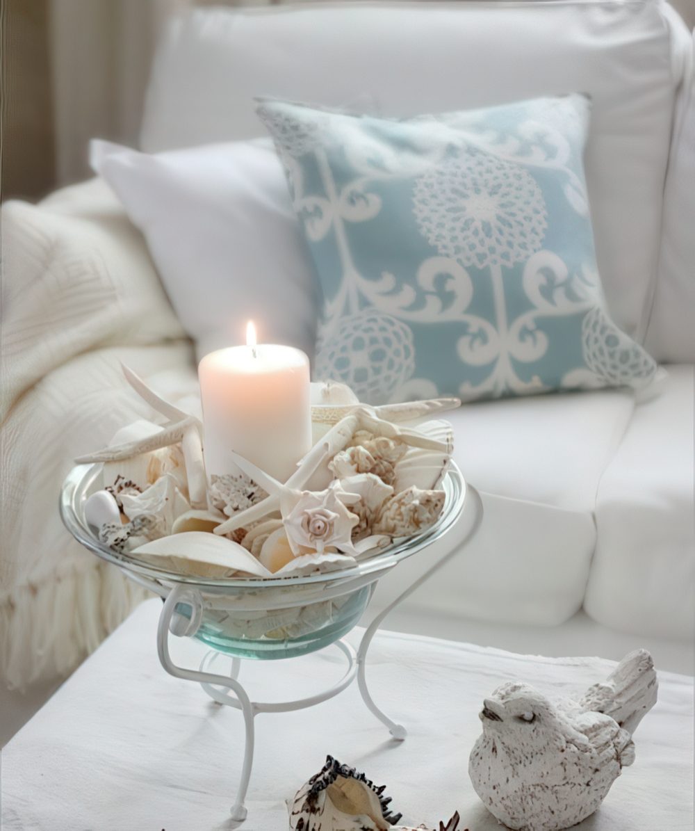 A cool seashell decoration - a blue glass bowl with seashells, starfish and a large candle inside it.