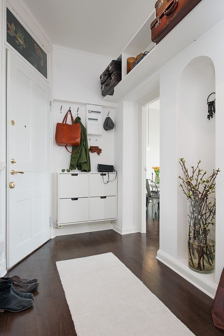 The wall behind the door is styled with an IKEA Stall cabinet and some hooks, and this is a whole basic entryway setup in a tiny nook.