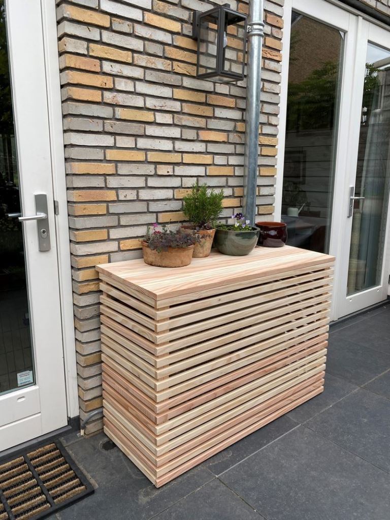 This outdoor slatted console perfectly matches the facade and displays some plants.