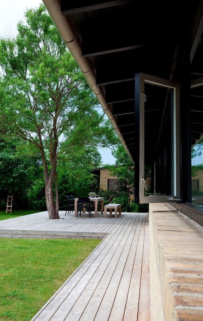 The long deck with a living tree and a dining space under it is a lovely outdoor spot to spend time.
