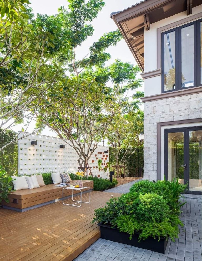 The deck is styled with a built-in bench, some trees and greenery, this is a simple and lovely spot to spend time in.