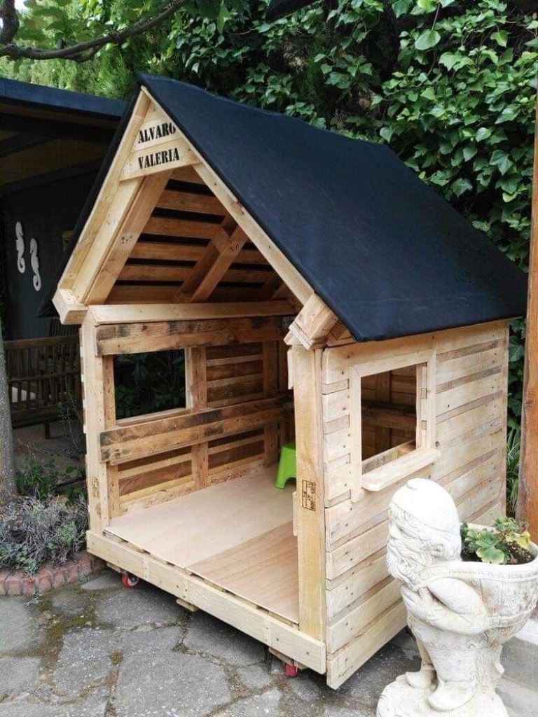 This stained mini house is built of palelts, and kids will love playing inside!.