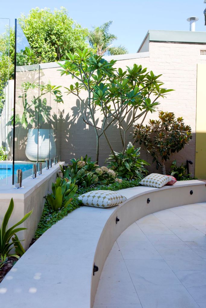 The modern space shows off plant arrangement between the pool and the bench. The curved bench elevates the style of the yard.